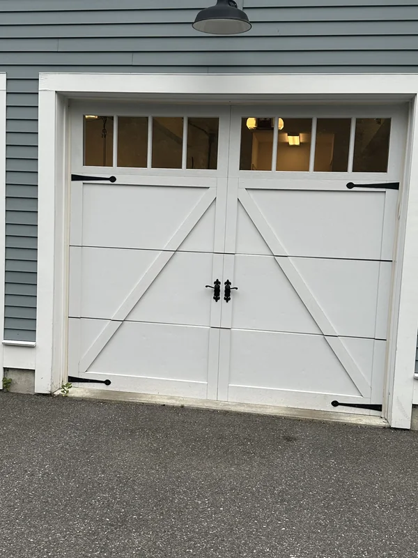 White single-carriage-style garage door with diagonal trim and windows.