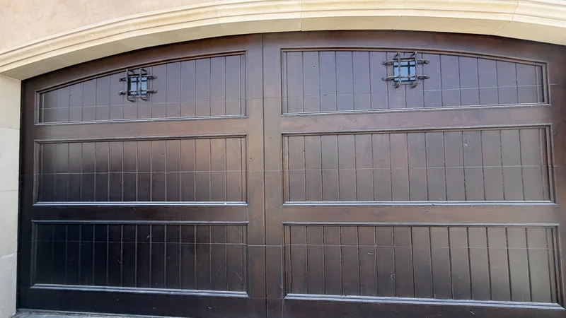 Brown carriage-style garage door with decorative window grilles.