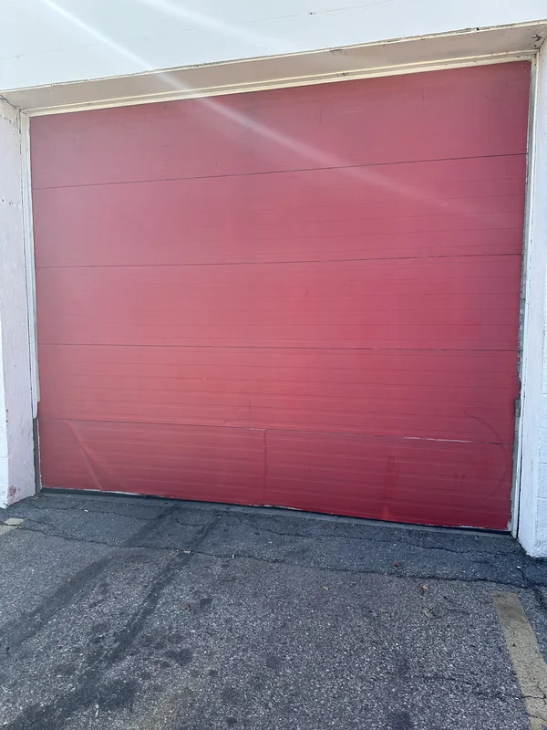 Red sectional garage door surrounded by white trim.