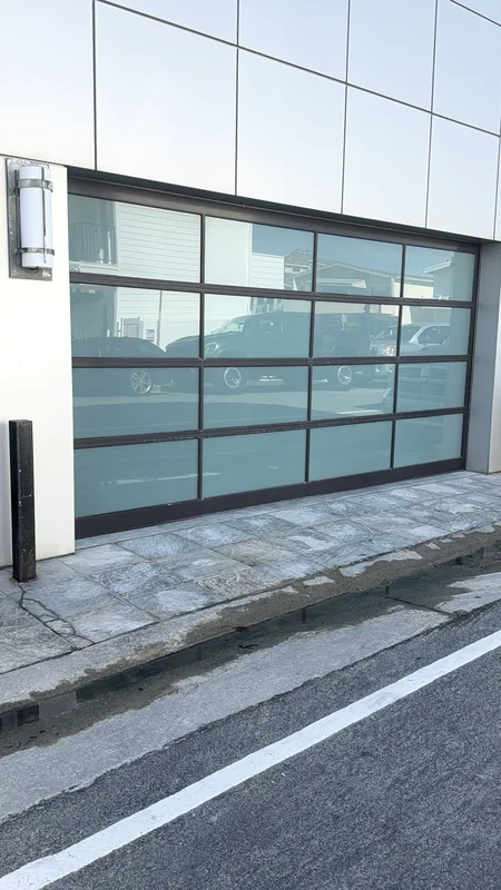Glass-panel garage door in a light-colored building facade.