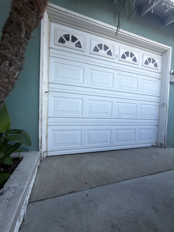 White raised-panel garage door with decorative fan-shaped window inserts.