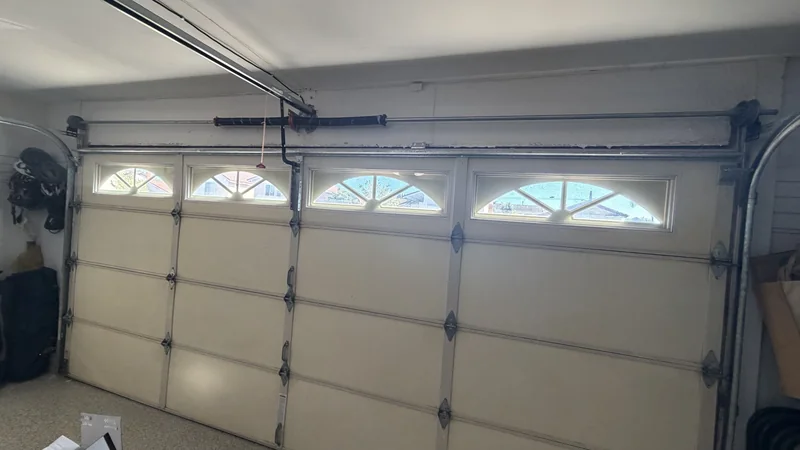 Interior of a sectional door showing hinges, tracks and overhead torsion springs.