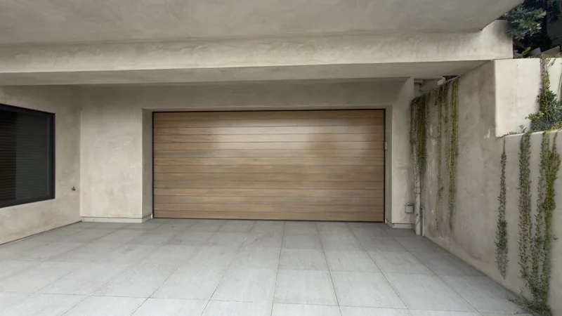 Horizontal wood-toned garage door recessed beneath a covered entry.