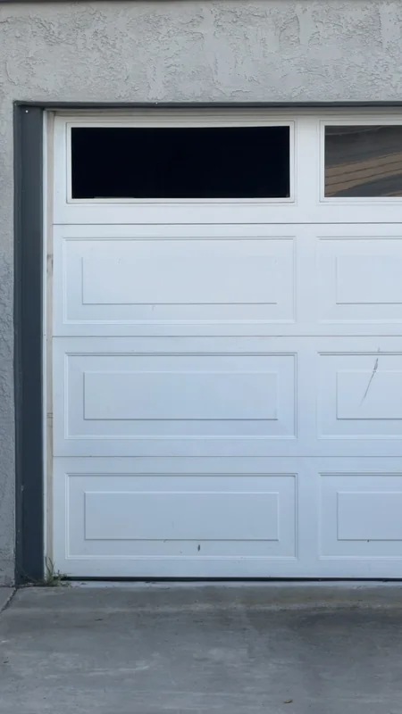Close view of a white garage door panel and rectangular top window.
