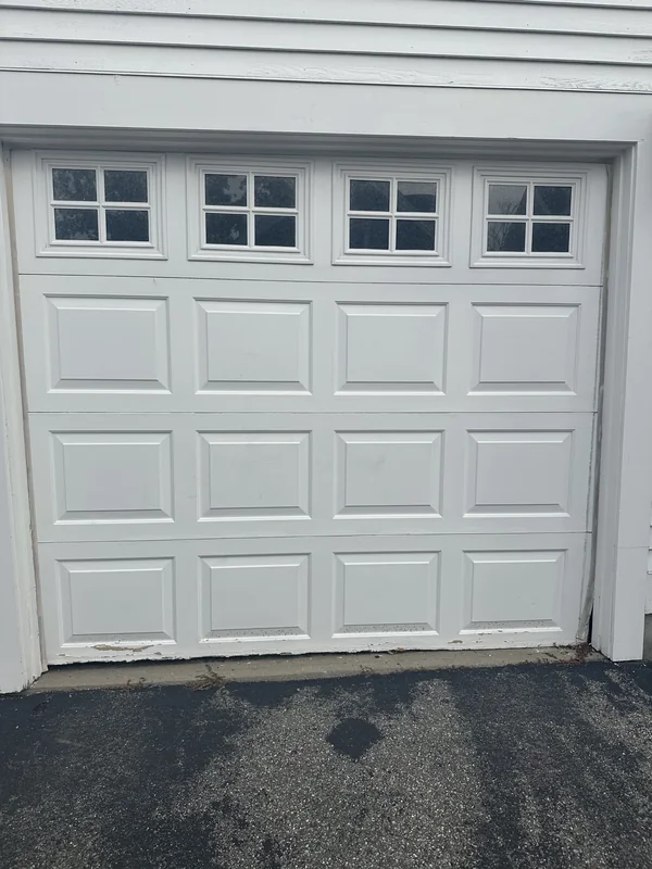 Single white raised-panel garage door with four divided windows.