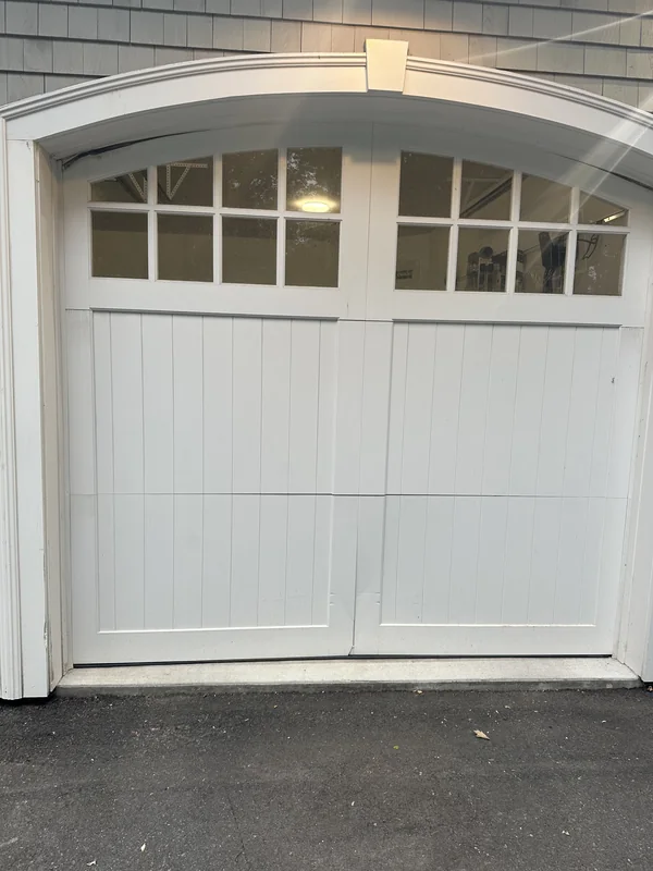 White carriage-style garage door with an arched frame and divided windows.