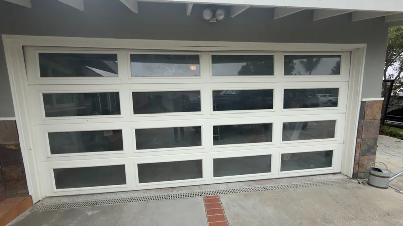 White-framed garage door with rows of rectangular glass panels.