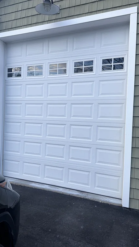 Tall white sectional garage door with a row of small divided windows.